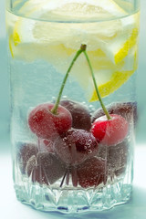 cool non-alcoholic drink with lemon lobules and cherries in air bubbles in a glass decoration