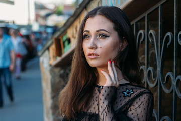 Fototapeta premium Emotional portrait of Fashion stylish portrait of pretty young woman. city portrait. sad girl. brunette in a black dress. expectation. dreams