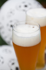 two glasses of beer and balloon with footballs - watching soccer