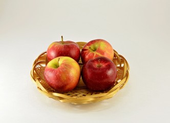 In a basket are four large apples, juicy with red sides.