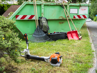 Motorsense und Gartenwerkzeug am Grünabfälle Container © Animaflora PicsStock
