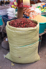 Dried red peppers in large sack on the market. Offer of paprika in the shop.