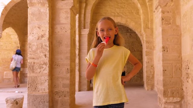 Girl eating ice-cream and walking in stone ribat of Sousse