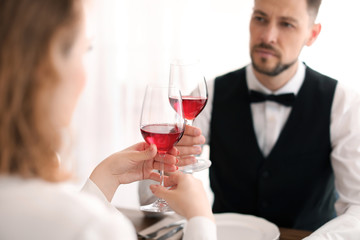 Young couple with glasses of delicious wine in restaurant