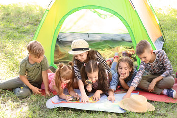 Little children with map near tent outdoors. Summer camp - obrazy, fototapety, plakaty
