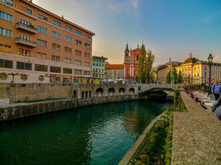 Fototapeta na wymiar Romantic Ljubljana's city center: river Ljubljanica, Triple Bridge (Tromostovje), Preseren square and Franciscan Church of the Annunciation; Ljubljana, Slovenia, Europe.
