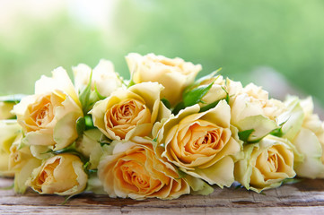 several yellow roses on a wooden table