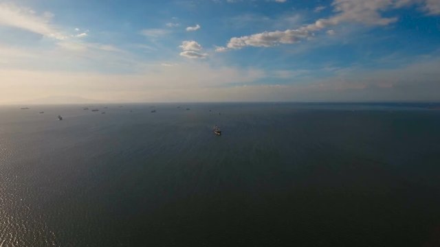 Aerial view Cargo ships in the Bay of Manila. Large container ship in the sea. Flying over the water surface of the sea with ships, blue sky and clouds. 4K video. Aerial footage. Philippines, Manila.