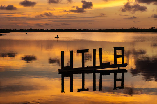Sunset at a lagoon with Utila letter sign with kanu in background, Utila, Honduras, Central America