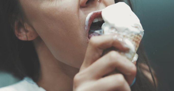 Young sporty girl holds a waffle cone with melt ice cream. Beautiful woman enjoys the taste of vanilla gelato. City style. 4K video shooting by handheld gimbal