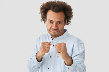 Attractive African American male ready to struggle, defenses girlfriend, keeps hands in fists, has...