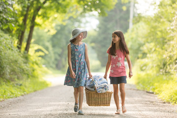 Two best friend sisters carrying a picnic basket together and talking