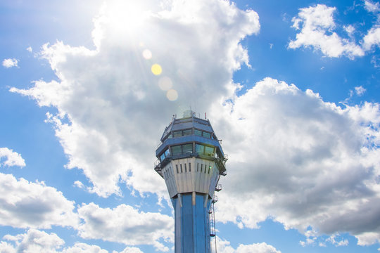 Airport traffic control tower with background of the sky and clouds sun shine glare.