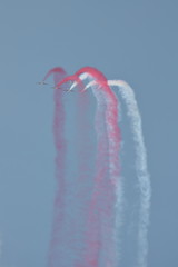 Eskadra szybkich sportowych samolotów wykonuje trudne akrobacje ne niebie rozsnuwając za sobą dym w polskich barwach narodowych, czerwonym i białym - obrazy, fototapety, plakaty