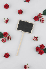 Small blackboard decorate with red rose paper flowers on white fabric with copy space