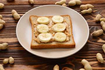 Fototapeta na wymiar Peanut butter toast with banana slices on wooden background
