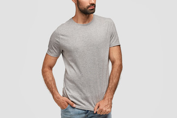 Design, advertisement and clothing concept. Cropped shot of bearded male dressed in casual t shirt...