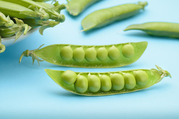 Two halves of a cracked pod of fresh peas on a blue background
