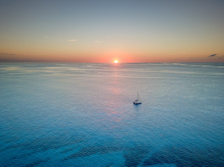 Sunset over the great barrier reef with a catamaran boat in the foreground. The sun is on the horizon. © Nicolas Faramaz