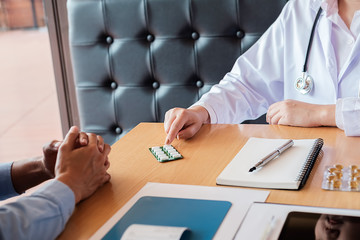 Patient listening intently to a male doctor explaining patient symptoms or asking a question as they discuss paperwork together in a consultation ..