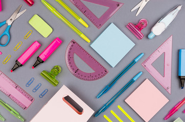 Neon multicolor stationery set as art pattern on grey background, flat lay.