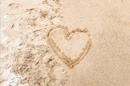 Heart drawn in the sand on the Beach background. Top view photo and space for text, love concept
