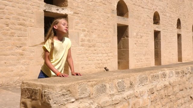 Young girl dancing and sitting on stone wall in ribat, Sousse, Tunisia