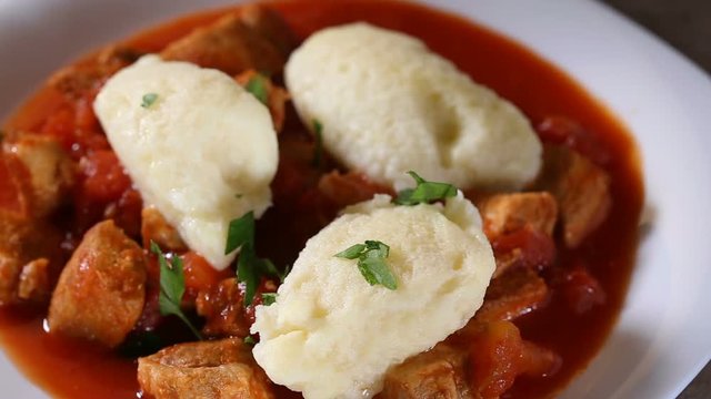 Spreading chopped fresh parsley over Traditional Hungarian food: Goulash with dumplings