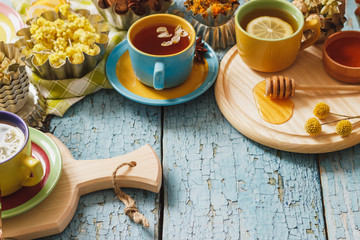 Cups with herb tea and pieces of lemon, dried herbs and different decorations