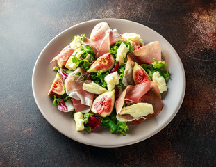 Fresh figs salad with prosciutto, green mix and cheese in a plate