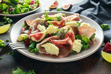 Fresh figs salad with prosciutto, green mix and cheese in a plate