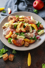 Fresh grilled peach salad with green mix, cheese, prosciutto and crouton