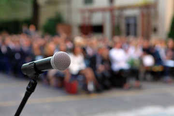 Microphone and stand in front of graduation ceremony audience against a background of auditorium