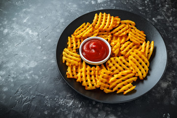 Crispy Potato Waffles Fries with Ketchup in a black plate