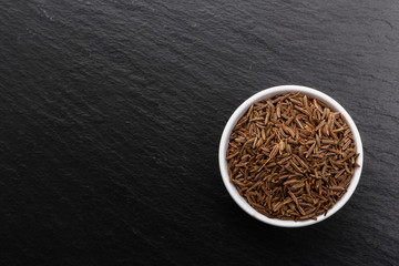 Seeds of cumin on a dark stone background