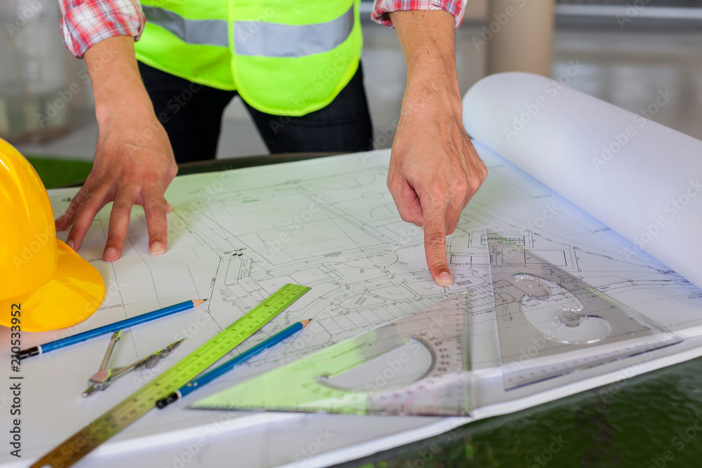 Wall mural architect engineer and head constructor working on a building site holding a blueprints at construct