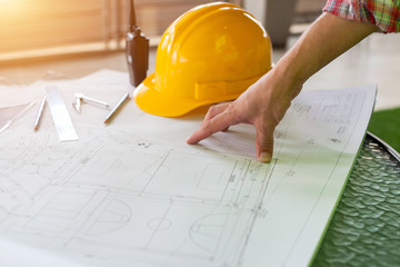 Architect engineer and head constructor working on a building site holding a blueprints at construction site.Close-up of Architect engineer drawing plan on blue print with architect equipment