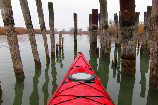 Bow of the red kayak against the background of the pillars of the remains of the old pier. Top view
