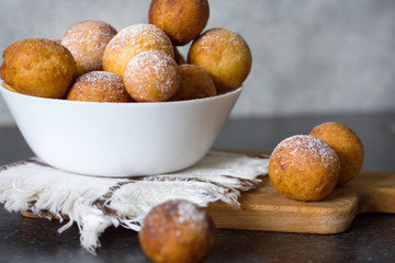 Donuts close-up. Italian fritters -Castagnole, traditional dish on a gray background in a white bowl on a wooden board.