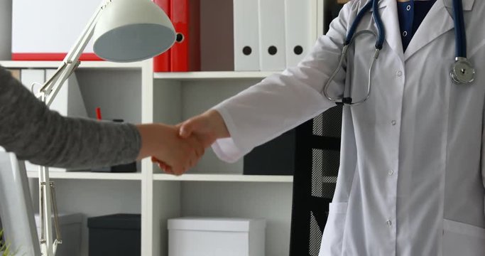 Cropped image of doctor and patient shake hands in office.