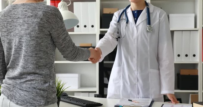Cropped image of doctor and patient shake hands in office.