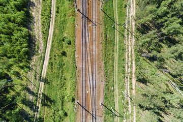 A railway track passing through the forest and field.