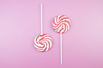 Flat lay top view tasty appetizing concept, minimal Sweet Treat Swirl Candy Lollipop marshmallow Colorful pattern on pink pastel background and copy space.