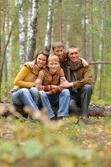Fototapeta premium Happy smiling family in autumn forest sitting 