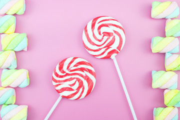 Flat lay top view tasty appetizing concept, minimal Sweet Treat Swirl Candy Lollipop marshmallow Colorful pattern on pink pastel background and copy space.