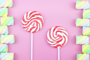 Flat lay top view tasty appetizing concept, minimal Sweet Treat Swirl Candy Lollipop marshmallow Colorful pattern on pink pastel background and copy space.