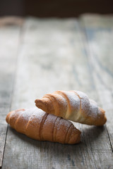 Two croissants on old wooden background