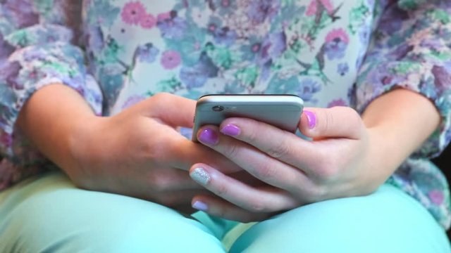Closeup shot of female hands holding smartphone, typing text on touch screen. Woman answering friend message in social network application, searching for information. Worker spending break time online