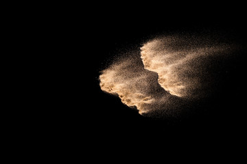 Golden sand explosion isolated on black background. Abstract sand cloud. Golden colored sand splash...