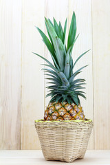 Ripe pineapple in basket on  wood background.